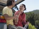 Young couple sitting in back of car holding water bottles and laughing