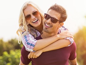 Closeup of young man carrying beautiful woman on his back. Smiling girl piggyback on guy while looking at camera.