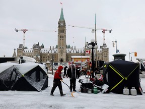 A demonstrator clears snow from around a shelter as truckers and supporters continue to protest COVID-19 vaccine mandates in Ottawa February 3, 2022.