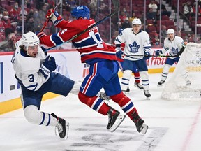 Canadiens' Nick Suzuki (right) delivers a hit on Maple Leafs' Justin Holl during the second period at the Bell Centre on Monday, Feb. 21, 2022 in Montreal.