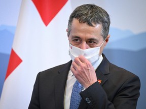 Swiss President Ignazio Cassis adjusts his mask during a press conference in Geneva on January 21, 2022.