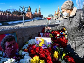 People lay flowers at the site where late opposition leader Boris Nemtsov was fatally shot on a bridge near the Kremlin in central Moscow on Feb. 27, 2022, on the seventh anniversary of his assassination.