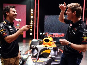 A handout photograph taken on January 26, 2022 and released on February 9, 2022 by Red Bull shows Formula one Red Bull's Dutch driver Max Verstappen (R) and Red Bull Racing and Formula one Red Bull's Mexican driver Sergio Perez (L), speaking during the launching presentation of the new Red Bull Racing RB18 car at Red Bull Racing Factory, in Milton Keynes, England.