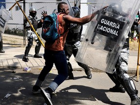 A migrant scuffles with a police officer in riot gear during a protest to demand speedy processing of humanitarian visas to continue on his way to the United States, outside the office of the National Migration Institute (INM) in Tapachula, Mexico February 22, 2022.
