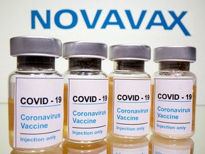 Vials with a sticker reading, "COVID-19 / Coronavirus vaccine / Injection only" and a medical syringe are seen in front of a displayed Novavax logo in this illustration taken October 31, 2020.