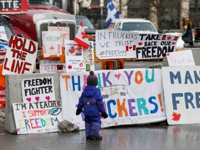 A young child looks at posters in support of the truckers, as truckers and supporters continue to protest COVID-19 vaccine mandates, in Ottawa, Wednesday, Feb. 9, 2022.