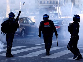 A French anti-riot policeman fires a tear gas canister on the Champs Elysees in Paris on February 12, 2022 as convoys of protesters so called "Convoi de la Liberte" arrived in the French capital