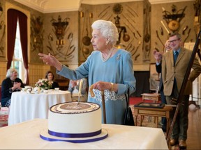 Queen Elizabeth II cuts a cake to celebrate the start of the Platinum Jubilee during a reception in the Ballroom of Sandringham House in King's Lynn, England, Feb. 5, 2022.