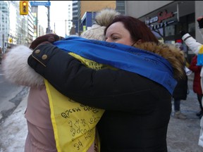 Tatiana Lipman, right, a Ukraine-Canadian demonstrator hugs and wraps a flag around her friend outside the Russian consulate on St. Clair Ave. E. just east of Yonge St. voice their displeasure with Russian leader Vladimir Putin and his full-scale invasion with Russian Forces attacking the Ukraine  on Thursday Feb. 24, 2022.