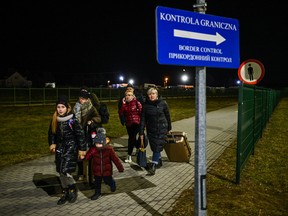Ukrainian citizens carry suitcases after crossing the Polish border on February 24, 2022 in Medyka, Poland.