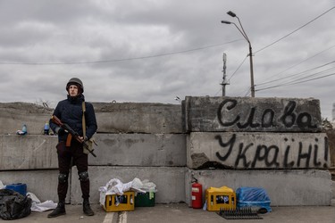 A member of a Territorial Defence unit guards a barricade next to writing saying " Glory To Ukraine" close to the eastern frontline in Kyiv, Saturday, on March 5, 2022.