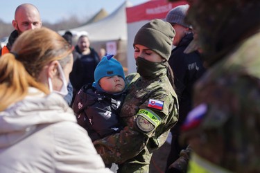 A Slovak police officer holds a baby as people fleeing the Russian invasion of Ukraine arrive at a border crossing in Vysne Nemecke, Slovakia, Sunday, March 6, 2022.