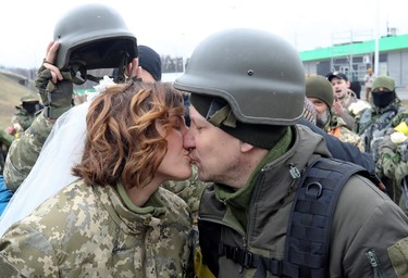 Members of the Ukrainian Territorial Defence Forces Lesia Ivashchenko and Valerii Fylymonov kiss at their wedding during Ukraine-Russia conflict, at a checkpoint in Kyiv, Ukraine, Sunday, March 6, 2022.