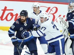 Adam Brooks, here battling Jets defenceman Jordie Benn during a game last season, is now a member of his hometown Winnipeg teams after being claimed on waivers for a fourth time already this season.