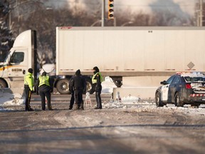 Police officers stand guard at a barricade along the road leading to the Ambassador Bridge border crossing in Windsor, Ont., Monday, Feb. 14, 2022.