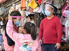 A woman tries on a face shield to protect against Covid-19 on a street in Hong Kong on February 25, 2022, as yet another record high number of new Covid-19 infections were recorded in the city.