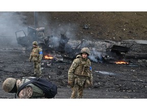 Ukrainian service members look for and collect unexploded shells after a fighting with Russian raiding group in the Ukrainian capital of Kyiv in the morning of Feb. 26, 2022, according to Ukrainian service personnel at the scene.