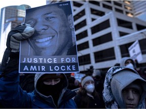 A demonstrator holds a photo of Amir Locke during a rally in protest of his killing, outside the Hennepin County Government Center in Minneapolis, Minn. Feb. 5, 2022.