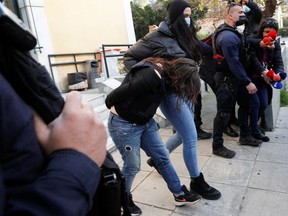 A couple accused of killing a 7-year-old child are escorted by police officers as they leave the prosecutors office, in Athens, Greece, February 15, 2022.