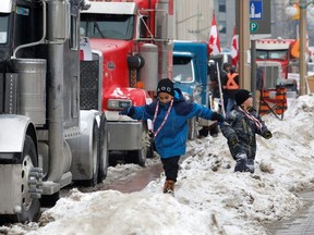 Children play on snow banks as truckers and their supporters continue to protest against the coronavirus disease (COVID-19) vaccine mandates, in Ottawa, Ontario, Canada, February 8, 2022.