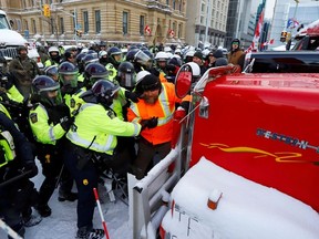 Canadian police push a protestor against a truck in front of Parliament Hill as police work to restore normality to the capital as trucks and demonstrators continue to occupy the downtown core to protest COVID-19 restrictions in Ottawa, Ontario, Canada, February 19, 2022.