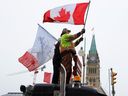 Menschen schwenken Fahnen auf einem Lastwagen vor dem Parliament Hill, während Lastwagenfahrer und ihre Unterstützer weiterhin gegen die COVID-19-Impfstoffmandate in Ottawa, Ontario, Kanada, am 6. Februar 2022 protestieren.  