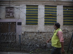 The Hindu symbol of well being Swastika is seen on a building as a Kashmiri man walks through a locality where many Kashmiri Hindu families used to live before the 1989 anti-India rebellion in Srinagar, Indian controlled Kashmir on Oct. 11, 2021.