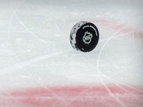 A view of a puck and the NHL logo and the face-off circle.