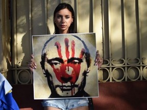 A protester holds a banner depicting Russian President Vladimir Putin during a demonstration  outside the Russian Embassy in Mexico City, on Feb. 28, 2022.