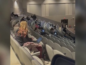 Screen shot of high school auditorium with maskless students socially distanced, separated from the other students