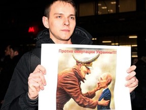 In Moscow on Thursday night a Russian man holds up a poster comparing Vladimir Putin to Hitler. GETTY IMAGES