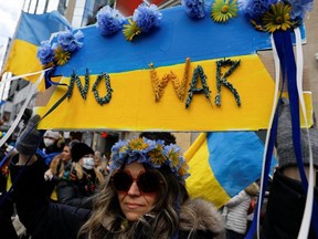 A woman holds up a placard decorated with flowers during an anti-war protest, after Russia launched a massive military operation against Ukraine, in Toronto, Ontario, Canada, February 27, 2022.