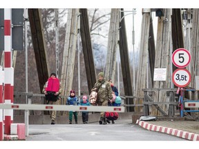 Ukrainische Soldaten helfen einer Frau und Kindern beim Grenzübertritt am Zollpunkt Sighetu Marmatiei in Baia Mare, Rumänien, 26. Februar 2022.