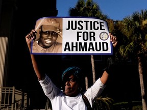 A woman holds a sign outside the Glynn County Courthouse after the jury reached a guilty verdict in the trial of William "Roddie" Bryan, Travis McMichael and Gregory McMichael, charged with the February 2020 death of 25-year-old Ahmaud Arbery, in Brunswick, Georgia, U.S., November 24, 2021.