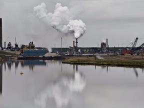The Syncrude oil sands extraction facility is reflected in a tailings pond near the city of Fort McMurray, Alberta on Sunday June 1, 2014.