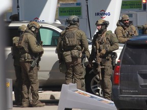 In this file photo taken on April 19, 2020, members of the RCMP tactical unit confer after the suspect in a deadly shooting rampage was neutralized at the Big Stop near Elmsdale, N.S.