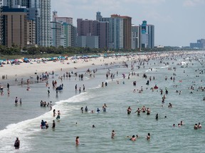 2020 m. liepos 4 d. Mirtl Biče, Pietų Karolinoje, žmonės braidžioja vandenyne.