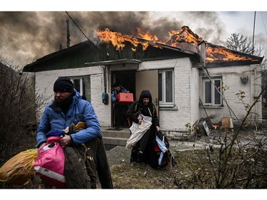People remove personal belongings from a burning house after being shelled in the city of Irpin, outside Kyiv, on March 4, 2022.