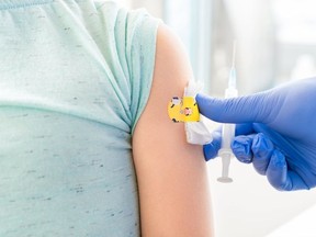 Vaccination of little girl in doctor's office. Kids funny adhesive plaster. Syringe with vaccine for covid-19 coronavirus,flu,dangerous infectious diseases. Injection. Clinical trials for human,child.
