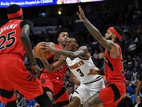 Denver Nuggets guard Bones Hyland (3) drives between Toronto Raptors forward Scottie Barnes (4) and Toronto Raptors guard Gary Trent Jr. (33) during the first quarter at Ball Arena.