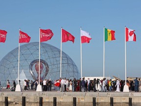 People gather during a flag-raising ceremony of the  newly-qualified countries for the 2022 World Cup in the Qatari capital Doha, on March 30, 2022. Traffic police nervously watched a World Cup crowd make a mark in Qatar's capital as FIFA set the scene for even bigger gatherings at the event by announcing that 800,000 tickets have already been sold.