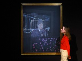 A gallery assistant poses with a painting by Francis Bacon revealing the artist's first treatment of the papal image, exhibited for the first time since it was painted in 1946 at the Gagosian gallery in London, March 15, 2022.