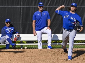 Blue Jays manager Charlie Montoyo (left) and pitching coach Pete Walker (centre) watch starting pitcher Kevin Gausman throw in the bullpen during a spring training workout.