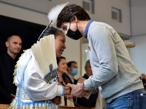 Prime Minister Justin Trudeau shakes hands with Sophie White following a ceremony at the Williams Lake First Nation, near the former St. Joseph's Mission Residential School, where an initial sweep had indicated 93 possible unmarked burial sites, in Williams Lake, B.C., March 30, 2022.