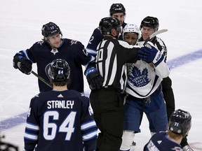 Toronto Maple Leafs' Wayne Simmonds (24) is held back by officials as he tries to get to Winnipeg Jets' Logan Stanley (64) during the third period of NHL action in Winnipeg on December 5, 2021.