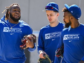 Toronto Blue Jays’ Vladimir Guerrero Jr., left, Cavan Biggio, center, and Teoscar Hernandez chat as they walk to a practice field during a spring training workout, Sunday, March 13, 2022, in Dunedin, Fla.