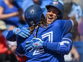 Toronto Blue Jays' Vladimir Guerrero Jr.  hugs George Springer outside the dugout after Springer's solo home run during the fifth inning of a spring training baseball game against the Detroit Tigers at TD Ballpark, in Dunedin, Fla., Friday, March 25, 2022.