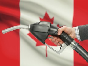 Fuel pump nozzle in hand with flag on background - Canada