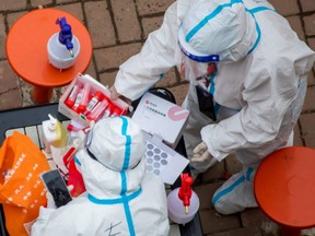 Medical workers prepare to conduct nucleic acid tests for COVID-19 for residents in Jilin, in China's northeastern Jilin province, Saturday, March 12, 2022.