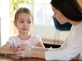 Unhappy small child girl sharing school problems with mom.